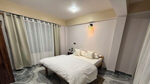 Ein Schlafzimmer mit einem Bett, Vorhängen, einem Nachttisch, einer Wandlampe und einem Boden mit Marmoroptik.