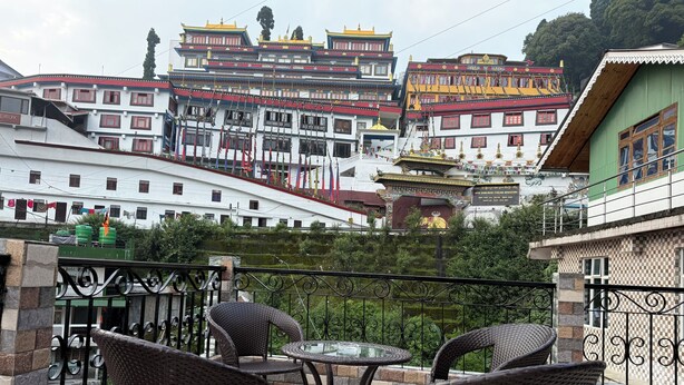 Eine Terrasse mit Korbstühlen und einem Tisch, mit Blick auf ein traditionelles Gebäude mit farbenfroher Architektur.