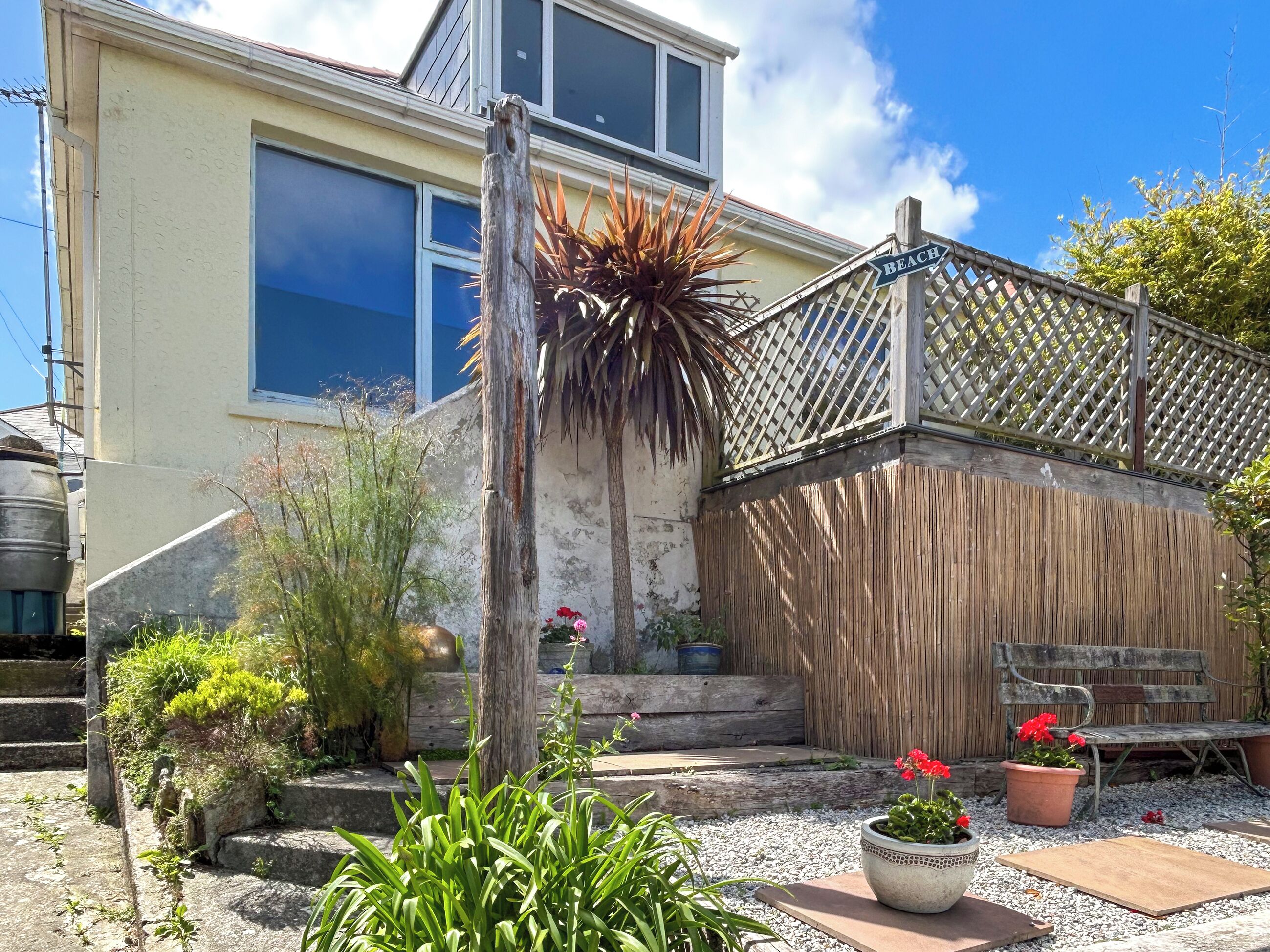 A house with a wooden fence, a bench, and potted plants.