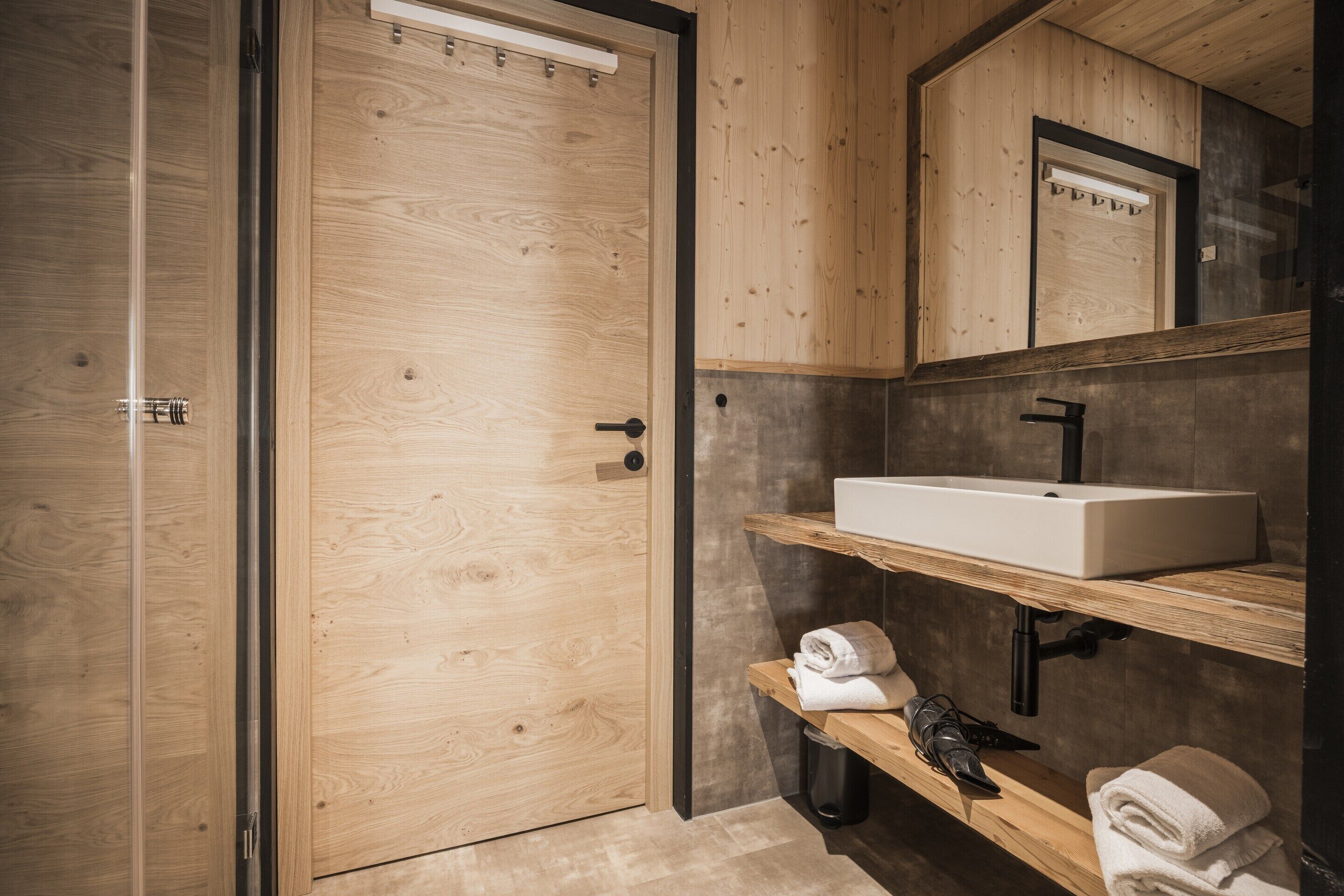 A wooden bathroom with a white sink, towel rack, and a mirror.