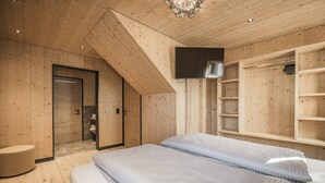 A modern bedroom with wooden walls, a flat-screen TV, a walk-in closet, and a bench. - Chalet With Mountain Scenery Your Bichelbach (Bichlbach)