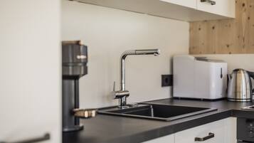 A modern kitchen with a black countertop, a stainless steel sink, a coffee maker, and a white toaster.