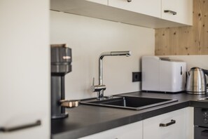 A modern kitchen with a black countertop, a stainless steel sink, a coffee maker, and a white toaster. - Chalet With Mountain Scenery Your Bichelbach (Bichlbach)