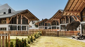 A row of wooden cabins with large windows, a wooden fence, and a mountain in the background. - Chalet With Mountain Scenery Your Bichelbach (Bichlbach)