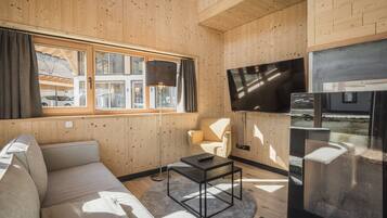 A modern interior with a wooden paneled wall, a sofa, a coffee table, a TV, and a chair.