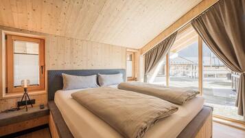 A wooden cabin bedroom with a bed, a window, and a tripod lamp.