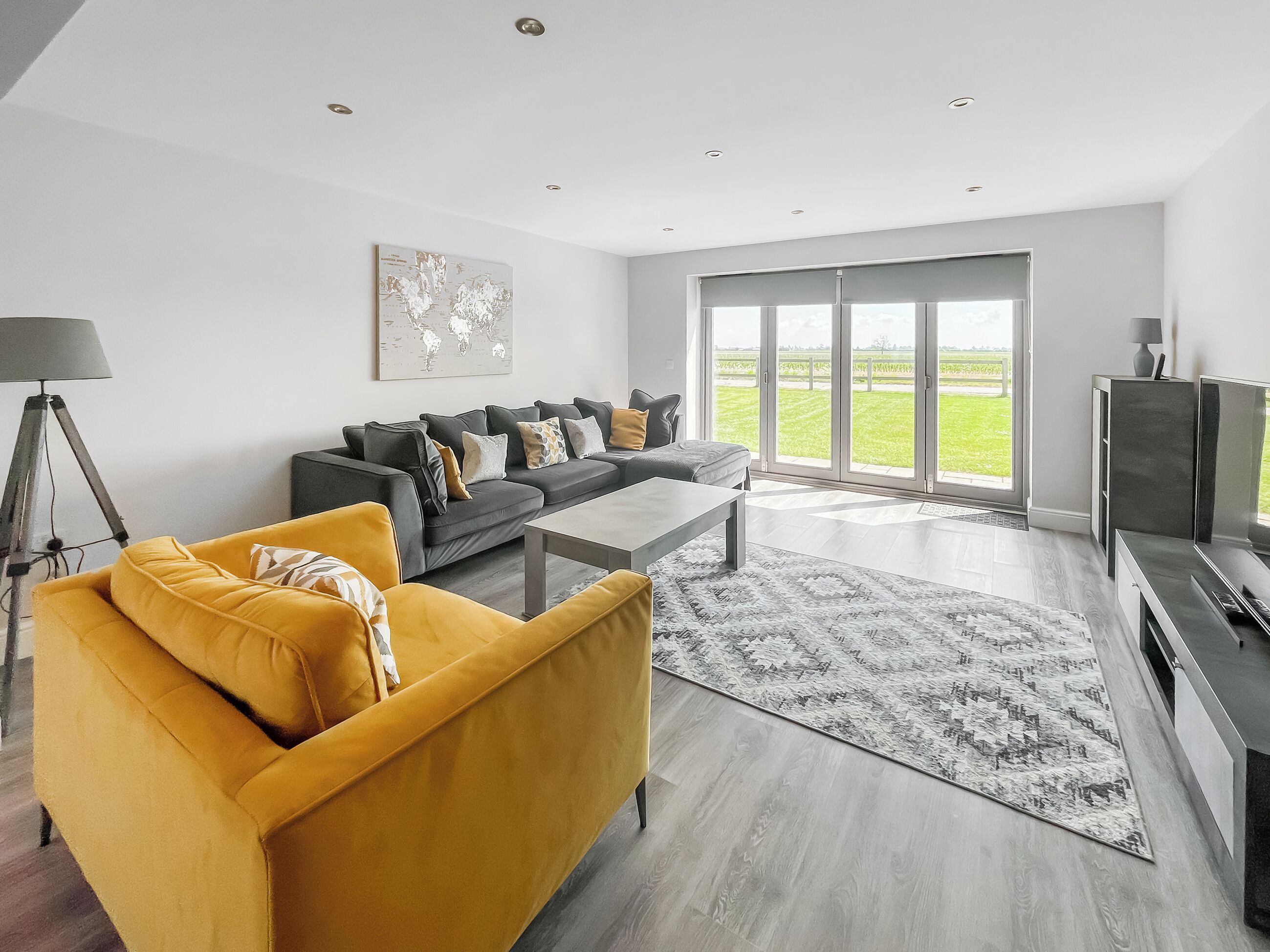 Een moderne woonkamer met een bank, salontafel en een groot raam met uitzicht op een groen veld.