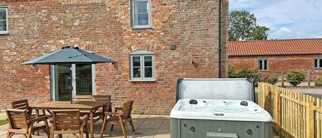 A brick house with a patio, a hot tub, and a wooden fence.