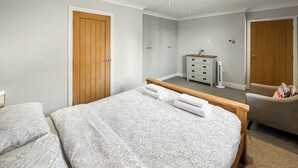Una camera da letto con un letto grande, due armadi, una cassettiera e una sedia.