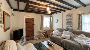 Ein gemütliches Wohnzimmer mit einer Couch, einem Holztisch, einem Fernseher und einer Wand mit Familienregeln.