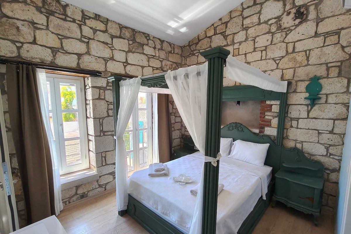 Una cama con dosel, una mesita de noche de madera y una pared de piedra.