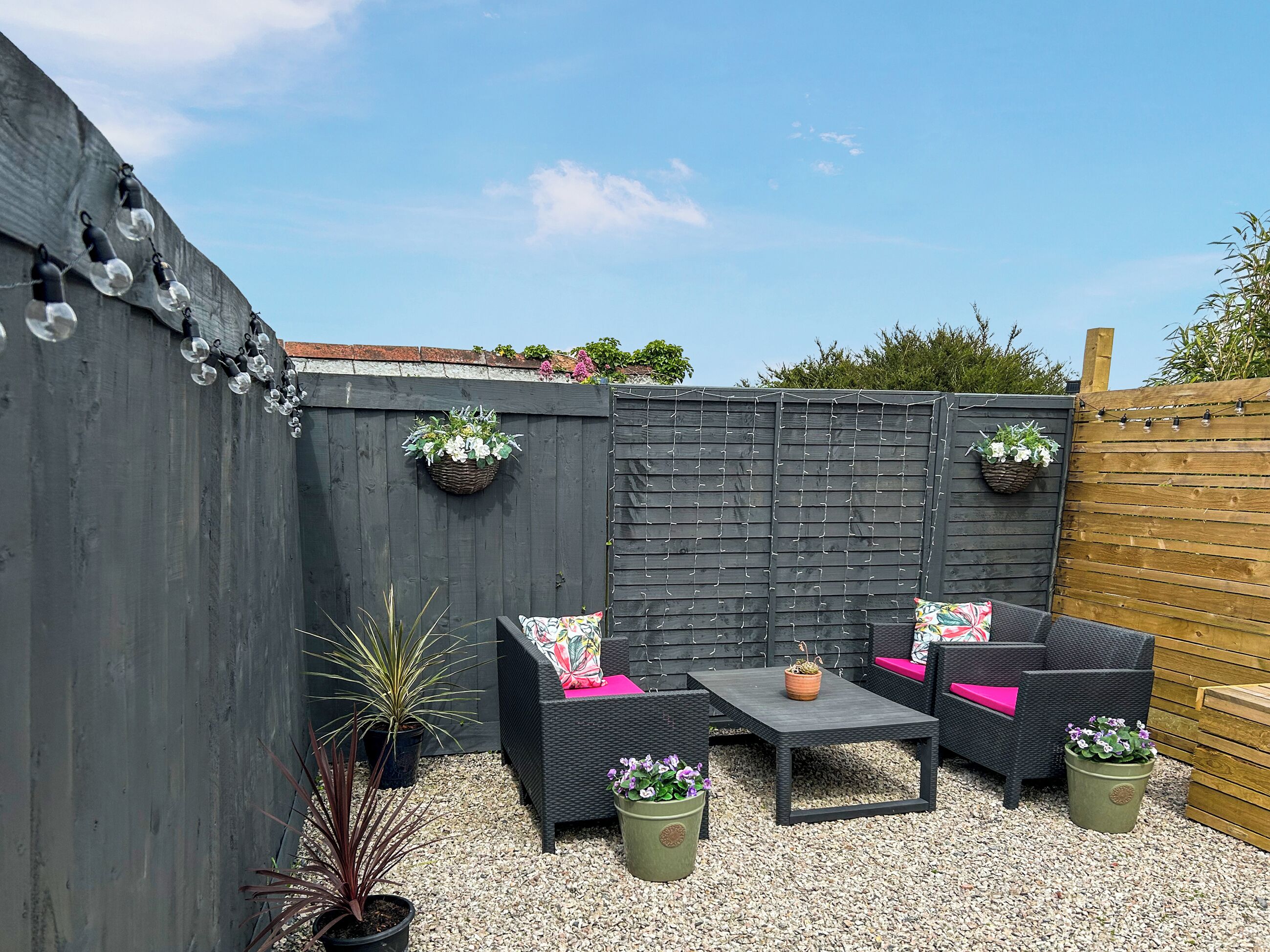 A patio with outdoor furniture, a table, and potted plants.