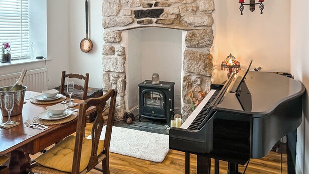 Un comedor con chimenea de piedra, un piano de cola y una zona de estar acogedora.