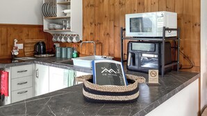 A kitchen with a microwave, coffee maker, and a basket with a book. - 1 bedroom accommodation in Rogart (Rogart)