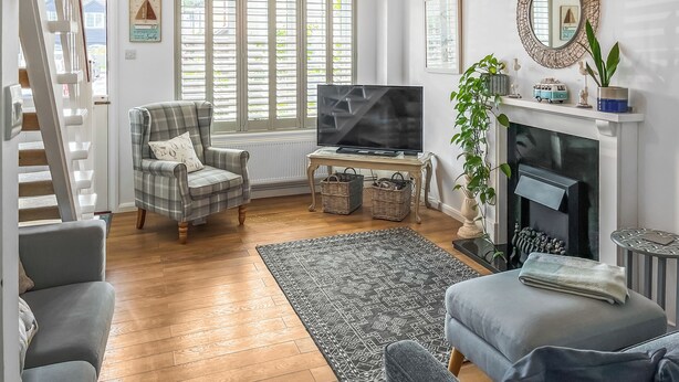 Een woonkamer met een televisie, een open haard, een trap en een groot raam met luiken.