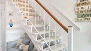 Een trap met witte leuningen en een houten handrail, die uitkomt op een plateau.