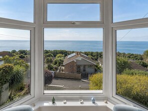 Une fenêtre donnant sur une maison et la mer.