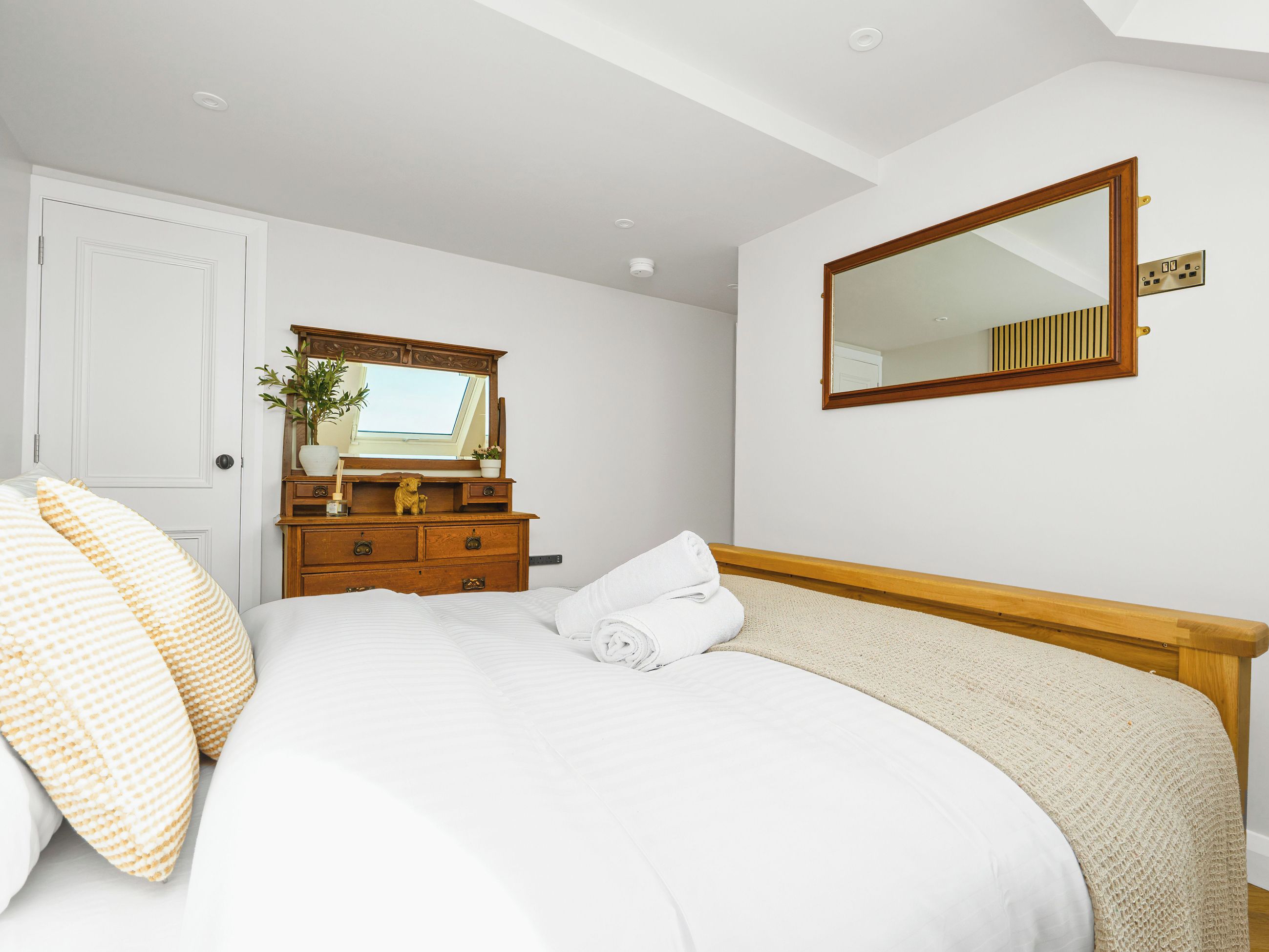 A bedroom with a bed, a dresser, a mirror, and a door.