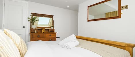 A bedroom with a bed, a dresser, a mirror, and a door.