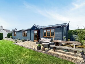 Ein blaues Haus mit einer Terrasse, einer Holzbank und einem Tisch.