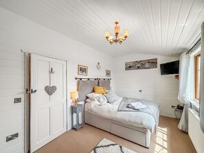 Ein Schlafzimmer mit Bett, Nachttisch, Lampe, Wandbild und Deckenleuchte.