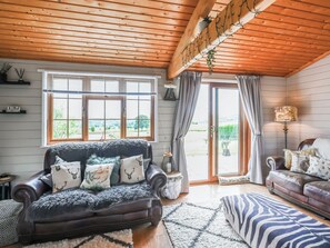 Ein gemütliches Wohnzimmer mit einer dunkelbraunen Ledersofa, einem gemusterten Teppich und einer Holzbalkendecke.