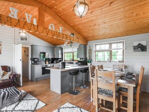 Eine geräumige Küche mit einer zentralen Kochinsel, Holzboden und einem Essbereich mit Tisch und Stühlen.