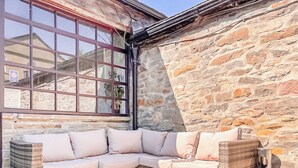Eine Sitzecke mit Rattanmöbeln und Kissen, eine Steinwand und ein Fenster mit Blick.