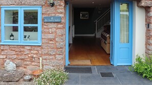 A stone building with a blue door and windows, a sign reading 'The Quarry Stables,' and a staircase leading inside. - 3 bedroom accommodation in Cheddar (Cheddar)