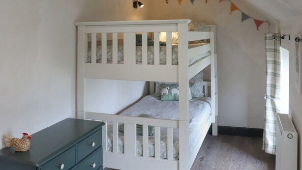 Een stapelbed met een onderbed, een kledingkast en een wandplank.