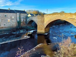 A stone bridge over a river with buildings on either side.