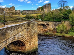 Un pont de pierre enjambant une rivière, avec un château historique en arrière-plan.