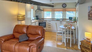 A modern kitchen with a dining area, a leather sofa, and a wooden side table. - 2 bedroom accommodation in Barnard Castle (Barnard Castle)