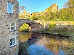 A stone bridge over a river, a stone building with windows, and a castle in the background. - 2 bedroom accommodation in Barnard Castle (Barnard Castle)