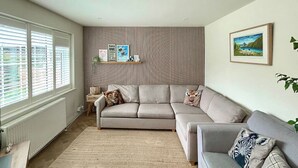 Ein Wohnzimmer mit einer Couch, einem Teppich, einer Heizung, einer Wand mit vertikalen Linien und einem gerahmten Bild.