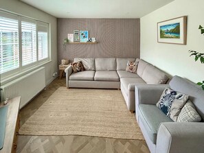 A living room with a sofa, a rug, a radiator, a wall with vertical lines, and a framed picture. - 4 bedroom accommodation in Addingham, near Ilkley (Addingham, near Ilkley)