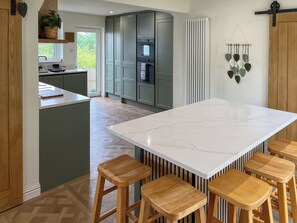 A modern kitchen with a large island, wooden stools, and a view of the outdoors. - 4 bedroom accommodation in Addingham, near Ilkley (Addingham, near Ilkley)