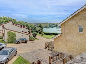 A residential area with a paved driveway, a parked car, and a view of a lake with boats. - 2 bedroom accommodation in Ryde (Ryde)