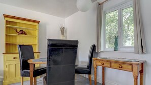 Ett rum med ett skrivbord, två stolar, en bokhylla och ett fönster med utsikt.