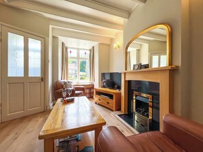 A living room with a fireplace, a television, a sofa, and a dining table.