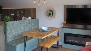 Uma cozinha moderna com forno embutido, uma área de refeições com banco e uma TV fixada na parede.
