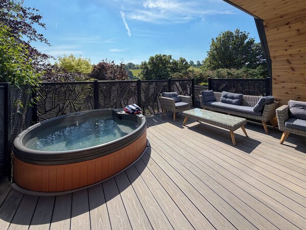 A wooden deck with a hot tub, wicker furniture, and a view of the countryside. - 2 bedroom accommodation in Pen-Y-Felin, near Mold (Pen-Y-Felin, near Mold)