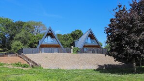 Uma casa moderna com telhado triangular e uma grande janela de vidro.