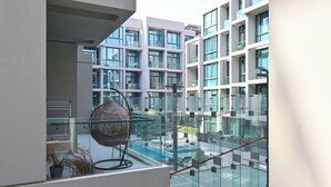 En modern byggnad med en glasfasad, en sfärisk skulptur och ett poolområde.