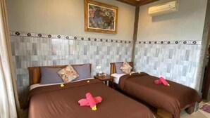 A hotel room with two beds, a painting on the wall, and an air conditioning unit.