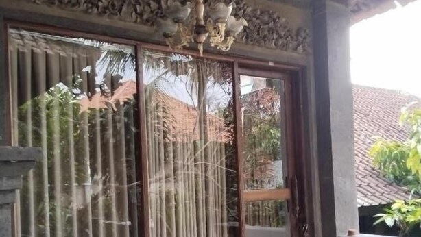 A room with a wooden table and two chairs, a large window with decorative glass panels, and a ceiling with intricate carvings.