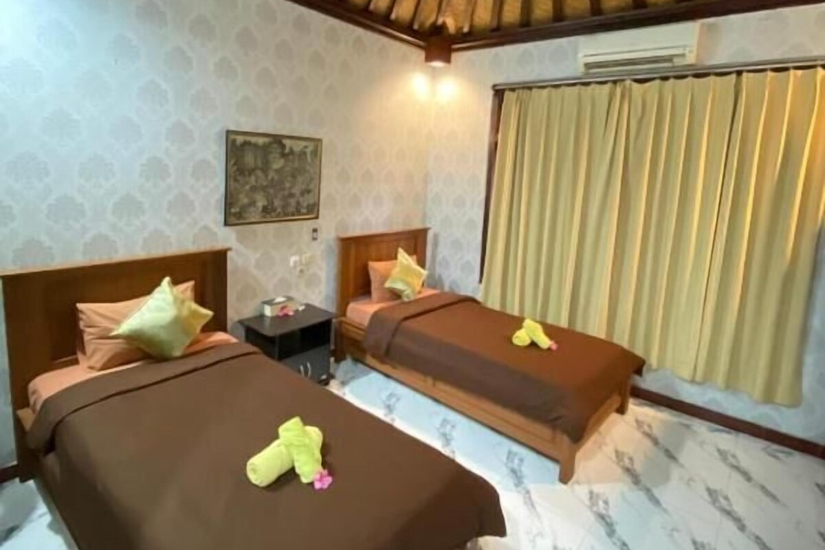 Habitación de hotel con dos camas, techo de madera, ventana con cortinas y suelo de mármol.