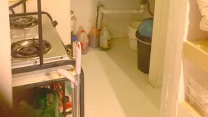 Une cuisine de taille réduite, équipée d’une cuisinière à gaz, d’un évier et de divers ustensiles de cuisine.