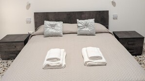 A neatly made bed with two pillows, a cityscape view, and a nightstand with a phone on it. - Koras 142 - Guest House: A beautiful, bright apartment in the heart of Sennori (Sennori)
