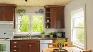 A kitchen with wooden cabinets, a stove, a sink, and a dining table with chairs.